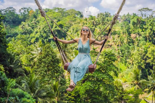 Young woman swinging in the jungle rainforest of Bali island, Indonesia. Swing in the tropics. Swings - trend of Bali.