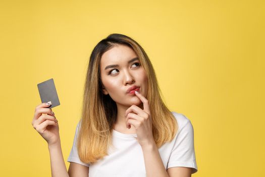 Young smiling beautiful Asian woman presenting credit card in hand showing trust and confidence for making payment