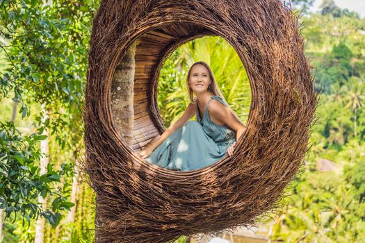Bali trend, straw nests everywhere. Young tourist enjoying her travel around Bali island, Indonesia. Making a stop on a beautiful hill. Photo in a straw nest, natural environment. Lifestyle.