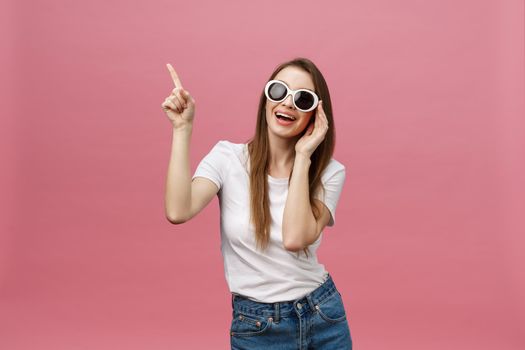 Cute young woman points a finger away isolate over pink background. Copy Space