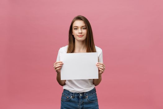 Close up portrait of positive laughing woman smiling and holding white big mockup poster isolated on pink background.