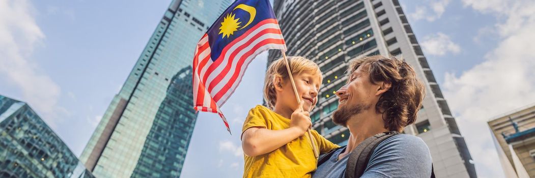 Dad and son tourists in Malaysia with the flag of Malaysia near the skyscrapers. Traveling with kids concept. BANNER, LONG FORMAT