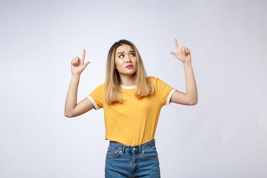 Young Asian woman looking angry and sad while pointing finger at camera isolated against white background