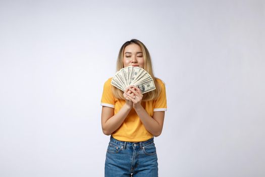 Asian woman holding cash notes isolated in white background. Young asian woman in white t-shirt in winning surprise, holding dollar note. Young rich hipster concept