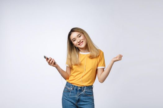 Portrait of a joyful satisfied asian woman in headphones listening to music and jumping isolated over white background.