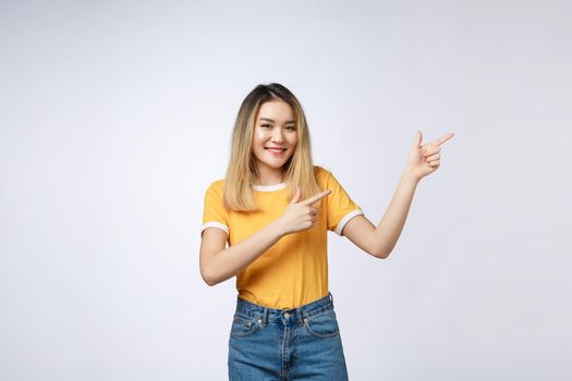 Beautiful young Asian woman pointing her finger up with cheerful expression, on white background