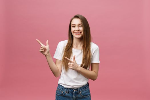 Photo of happy young woman standing and poiting finger isolated over pink background