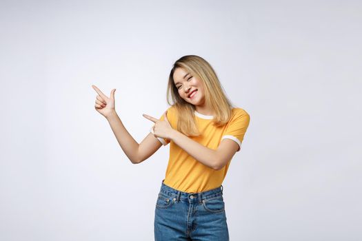 Beautiful young Asian woman pointing her finger up with cheerful expression, on white background