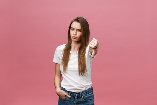 Unhappy woman giving thumbs down gesture looking with negative expression and disapproval