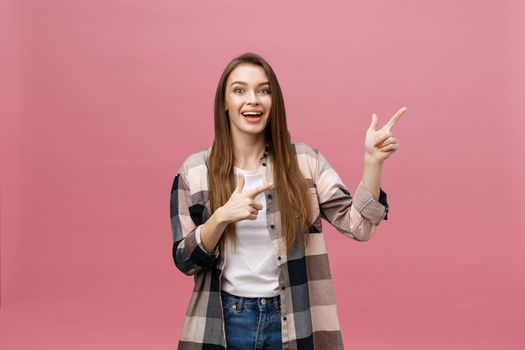 Cute young woman points a finger away isolate over pink background. Copy Space