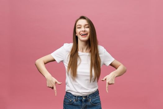 Photo of happy young woman standing and poiting finger isolated over pink background