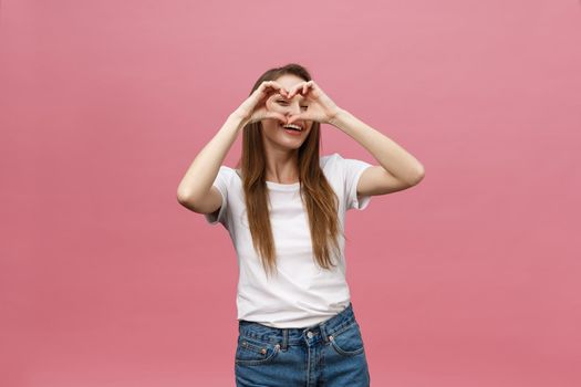 Lifestyle Concept: Beautiful attractive woman in white shirt making a heart symbol with her hands.