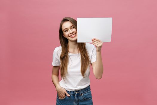 Close up portrait of positive laughing woman smiling and holding white big mockup poster isolated on pink background.