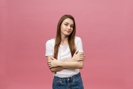 Portrait of a happy woman standing with arms folded isolated on a pink background.