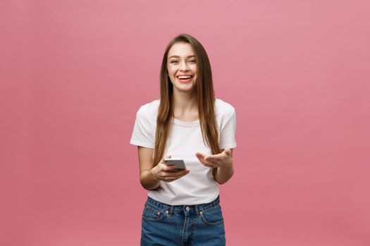 Photo of cheerful cute beautiful young woman chatting by mobile phone isolated over pink wall background