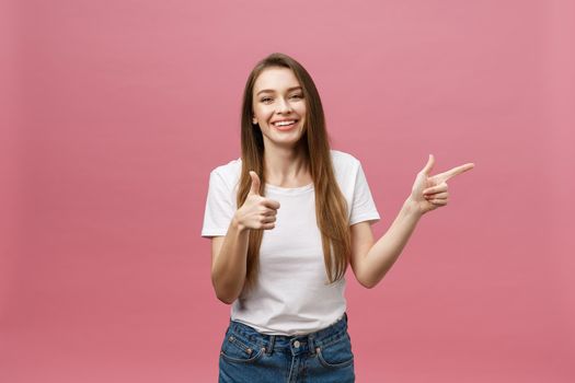 Photo of happy young woman standing and poiting finger isolated over pink background