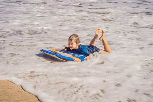 Happy Young boy having fun at the beach on vacation, with Boogie board.