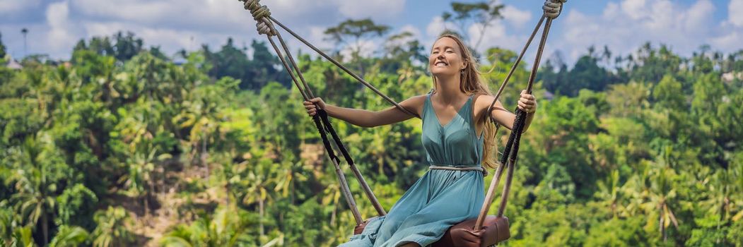 Young woman swinging in the jungle rainforest of Bali island, Indonesia. Swing in the tropics. Swings - trend of Bali. BANNER, LONG FORMAT