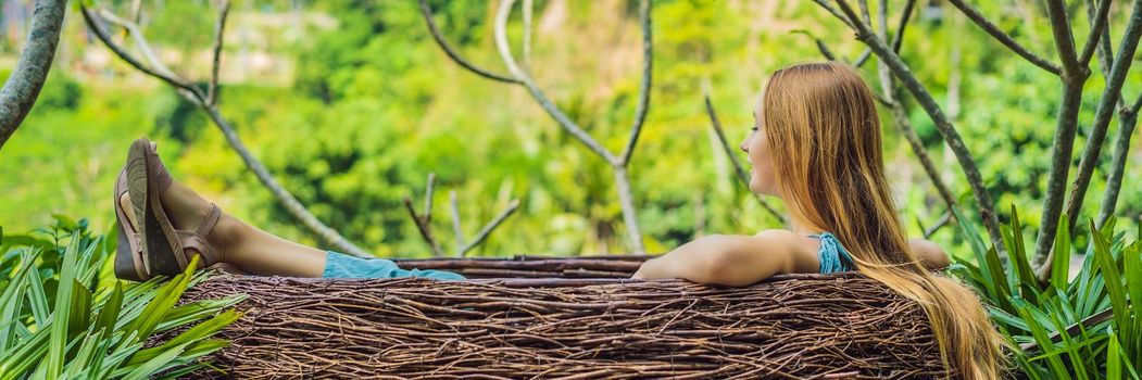 Bali trend, straw nests everywhere. Young tourist enjoying her travel around Bali island, Indonesia. Making a stop on a beautiful hill. Photo in a straw nest, natural environment. Lifestyle. BANNER, LONG FORMAT