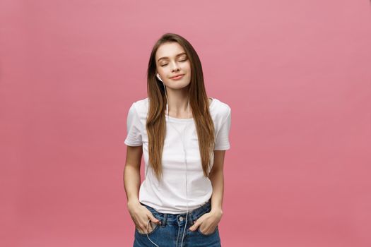 Lifestyle Concept. Young woman using phone for listening to music on pink background.