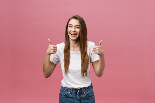 Happy young woman giving thumbs up on pink background