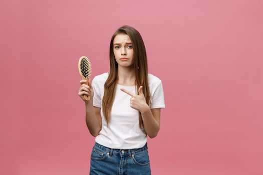 girl on a pink background with a comb for the hair, the hair problem.