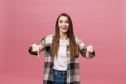 Cute young woman points a finger away isolate over pink background. Copy Space