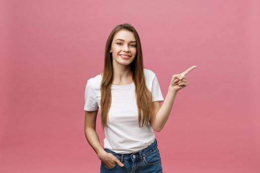 Photo of happy young woman standing and poiting finger isolated over pink background