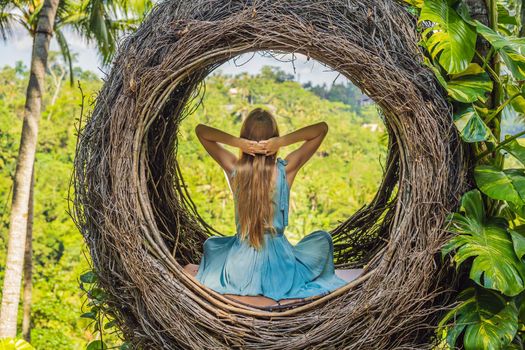 Bali trend, straw nests everywhere. Young tourist enjoying her travel around Bali island, Indonesia. Making a stop on a beautiful hill. Photo in a straw nest, natural environment. Lifestyle.