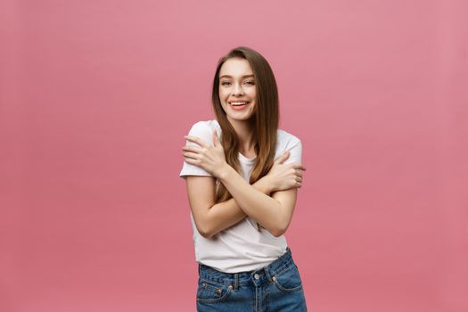 Portrait of a happy woman standing with arms folded isolated on a pink background.