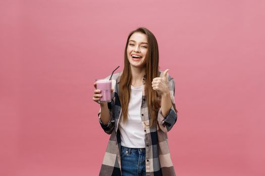 Young woman drinking juice smoothie with straw. Isolated studio portrait