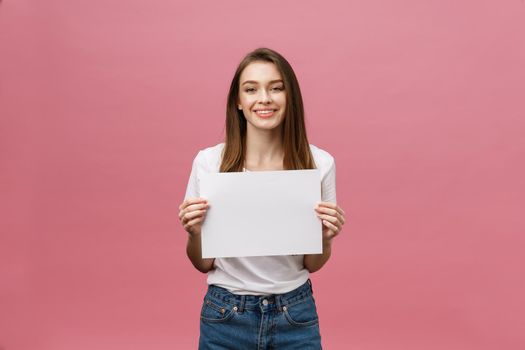Close up portrait of positive laughing woman smiling and holding white big mockup poster isolated on pink background.