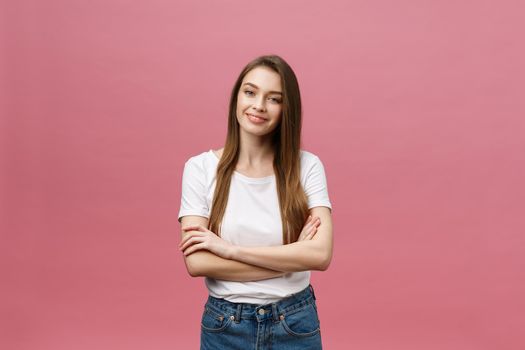 Portrait of a happy woman standing with arms folded isolated on a pink background.