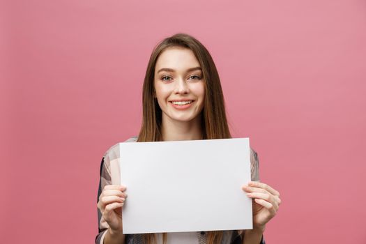 Close up portrait of positive laughing woman smiling and holding white big mockup poster isolated on pink background.