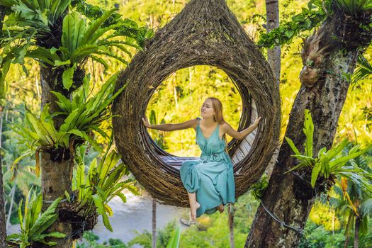 Bali trend, straw nests everywhere. Young tourist enjoying her travel around Bali island, Indonesia. Making a stop on a beautiful hill. Photo in a straw nest, natural environment. Lifestyle.