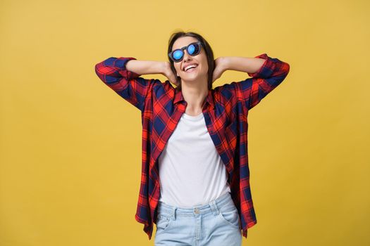 Happy stylish modern woman with modern shaped sunglasses laughing looking at you camera isolated on yellow background. Happiness concept.