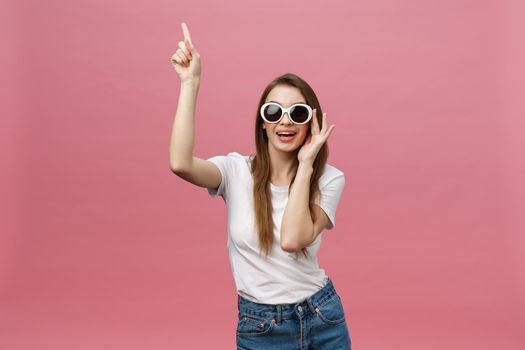 Cute young woman points a finger away isolate over pink background. Copy Space