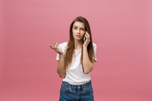 Serious young woman talking on phone isolated on pink. Copy space and fashion. Mock up