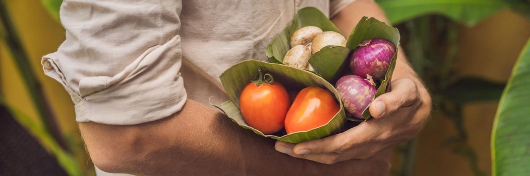 Eco-friendly product packaging concept. Vegetables wrapped in a banana leaf, as an alternative to a plastic bag. Zero waste concept. Alternative packaging. BANNER, LONG FORMAT