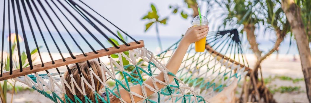 Young woman on the beach in a hammock with a drink. BANNER, LONG FORMAT