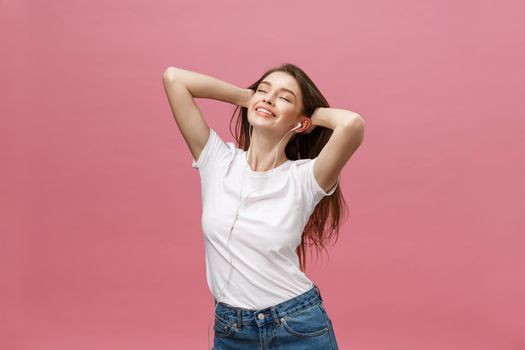 Lifestyle Concept. Young woman using phone for listening to music on pink background.