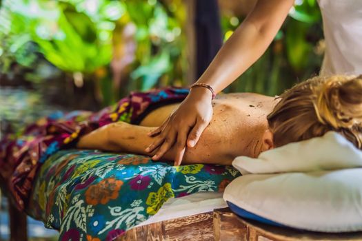 Young beautiful relaxing woman getting spa massage of shoulder in beauty salon.