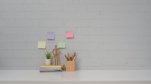 Personal accessories on white table and colorful sticky notes on brick wall background. Copy space for your advertise tex.