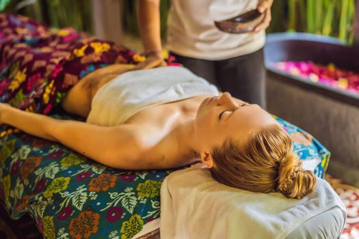 Young beautiful relaxing woman getting spa massage of shoulder in beauty salon.