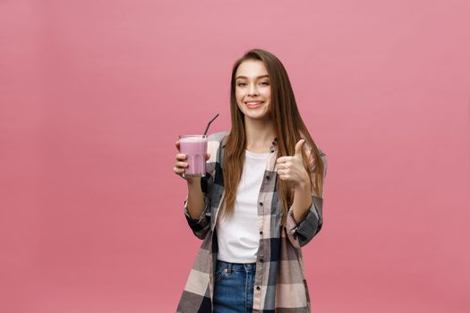 Young woman drinking juice smoothie with straw. Isolated studio portrait