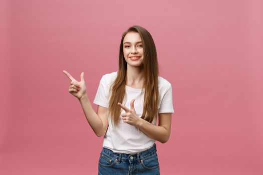 Photo of happy young woman standing and poiting finger isolated over pink background