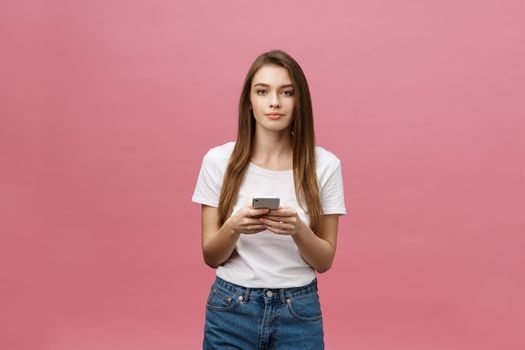 Photo of cheerful cute beautiful young woman chatting by mobile phone isolated over pink wall background