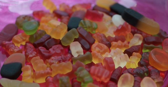 Mixed sweeties, colorful gummy candies on a pink glass plate. Gummy Sweeties, Jelly sweet, candy dessert. Gummy bears. Jelly gummy candies assortment.