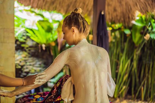 Young beautiful relaxing woman getting spa massage of shoulder in beauty salon.