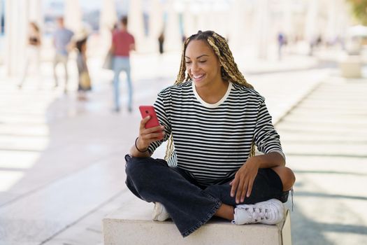 Young black female using a smartphone, wearing her hair in braids. Typical African hairstyle.